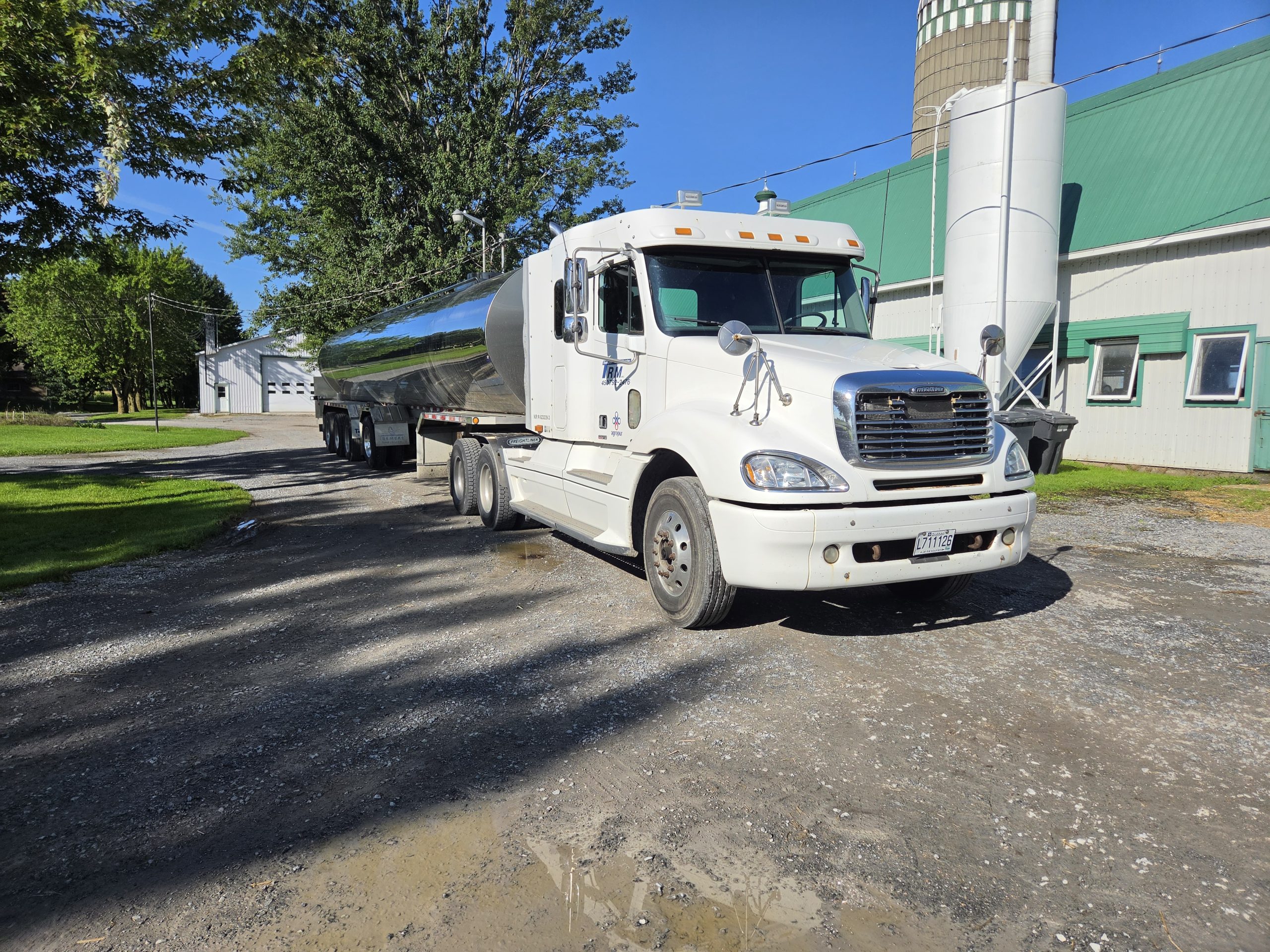 Camion-citerne de ramassage du lait stationné devant une ferme laitière québécoise