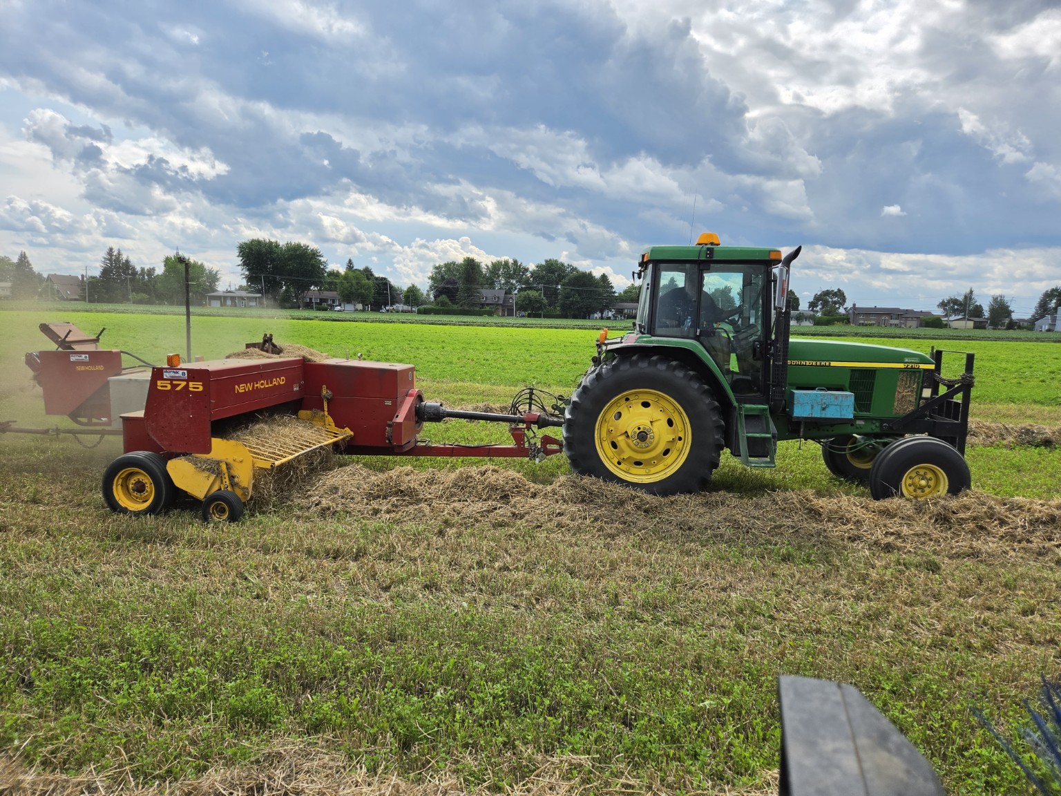 Le John Deere 7210 tire la presse New Holland 575 dans les andains de paille d’orge.